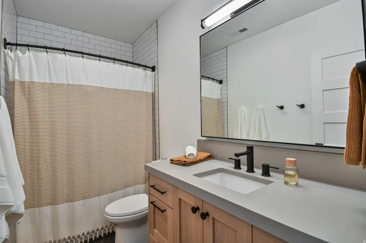 Bathroom featuring a light wood vanity with black hardware, an integrated sink, and a light gray countertop