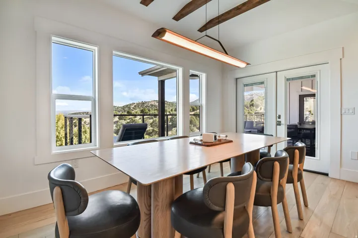 Spacious interior featuring a large wood-finish dining table, light wood-finish flooring, and exposed wood ceiling beams