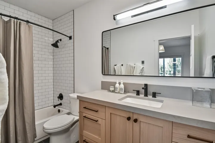 Bathroom featuring a light wood-finish vanity with a light countertop, an undermount sink, and matte black fixtures