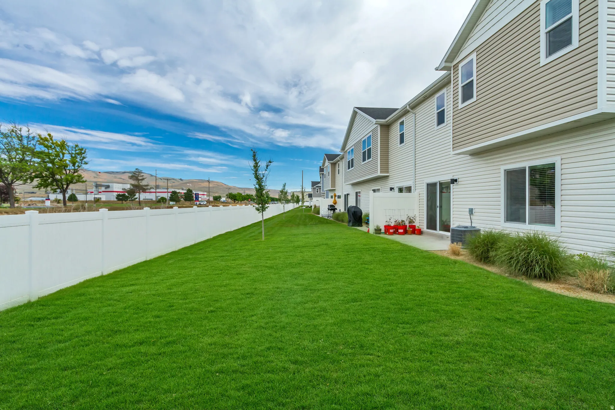End unit, no backyard neighbors featuring a spacious green lawn with a concrete patio directly accessible via two sliding glass doors