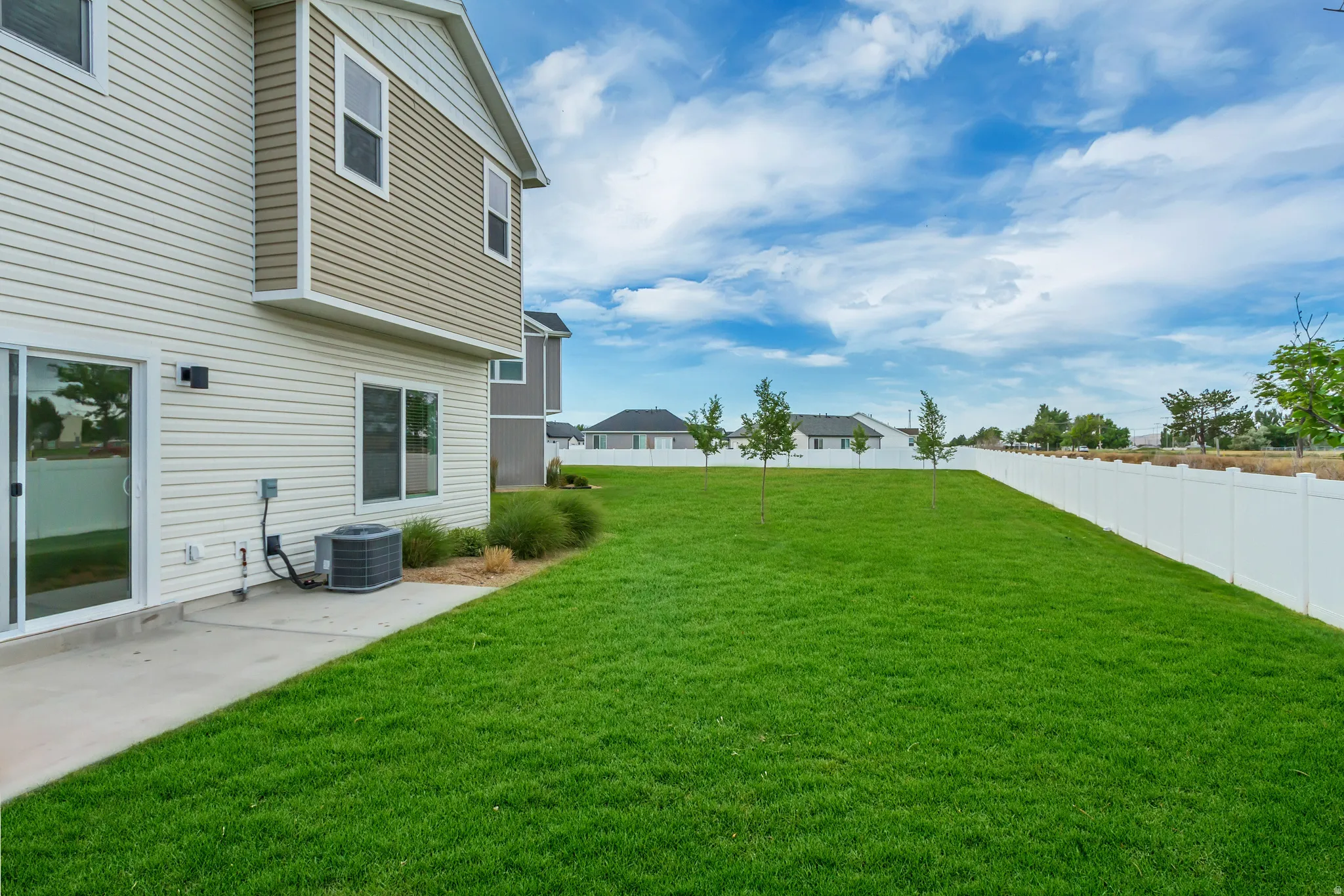 End unit, no backyard neighbors featuring a spacious green lawn with a concrete patio directly accessible via two sliding glass doors