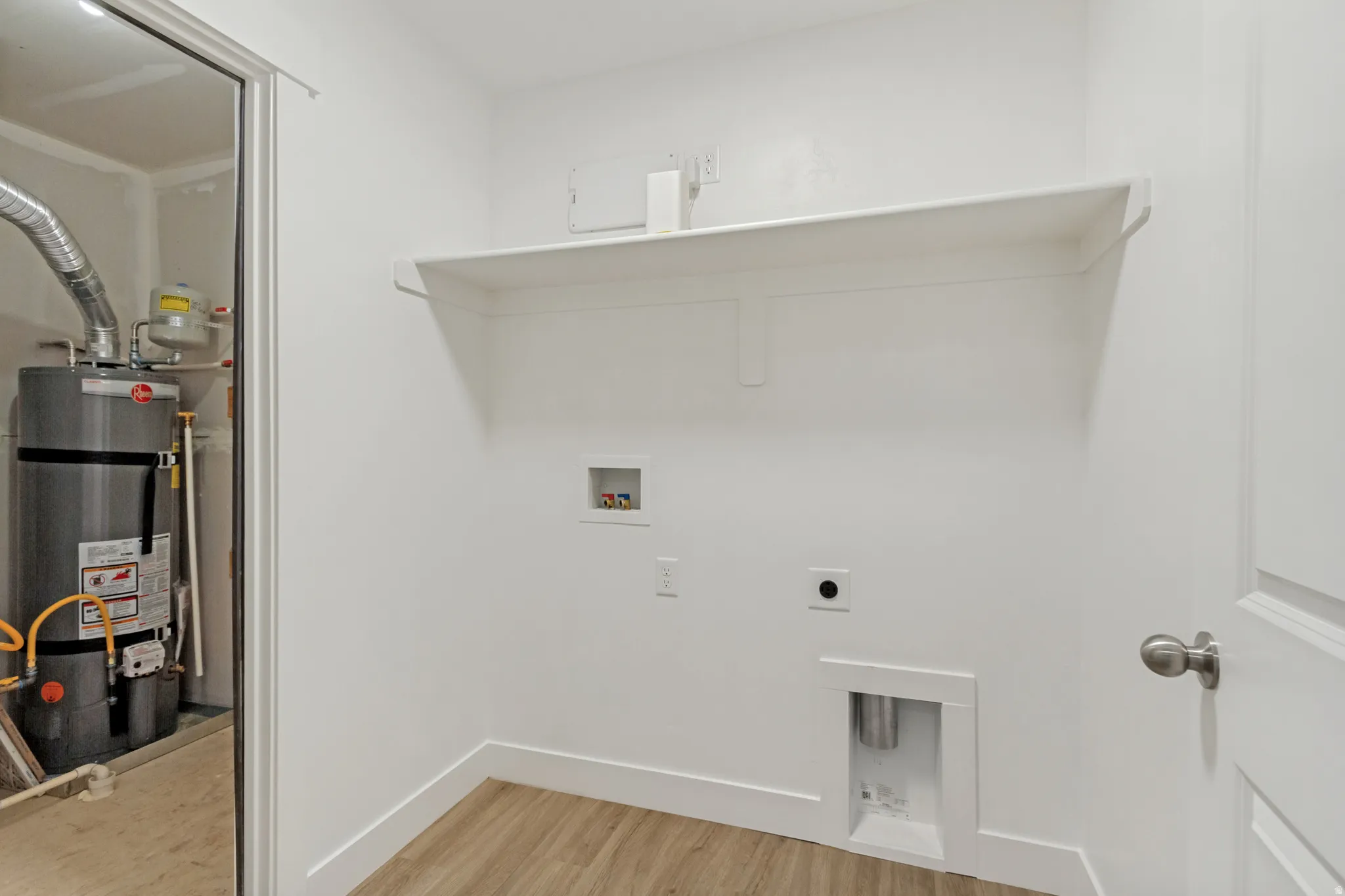 Dedicated utility space featuring laundry hookups, a built-in shelf, and wood-finish flooring