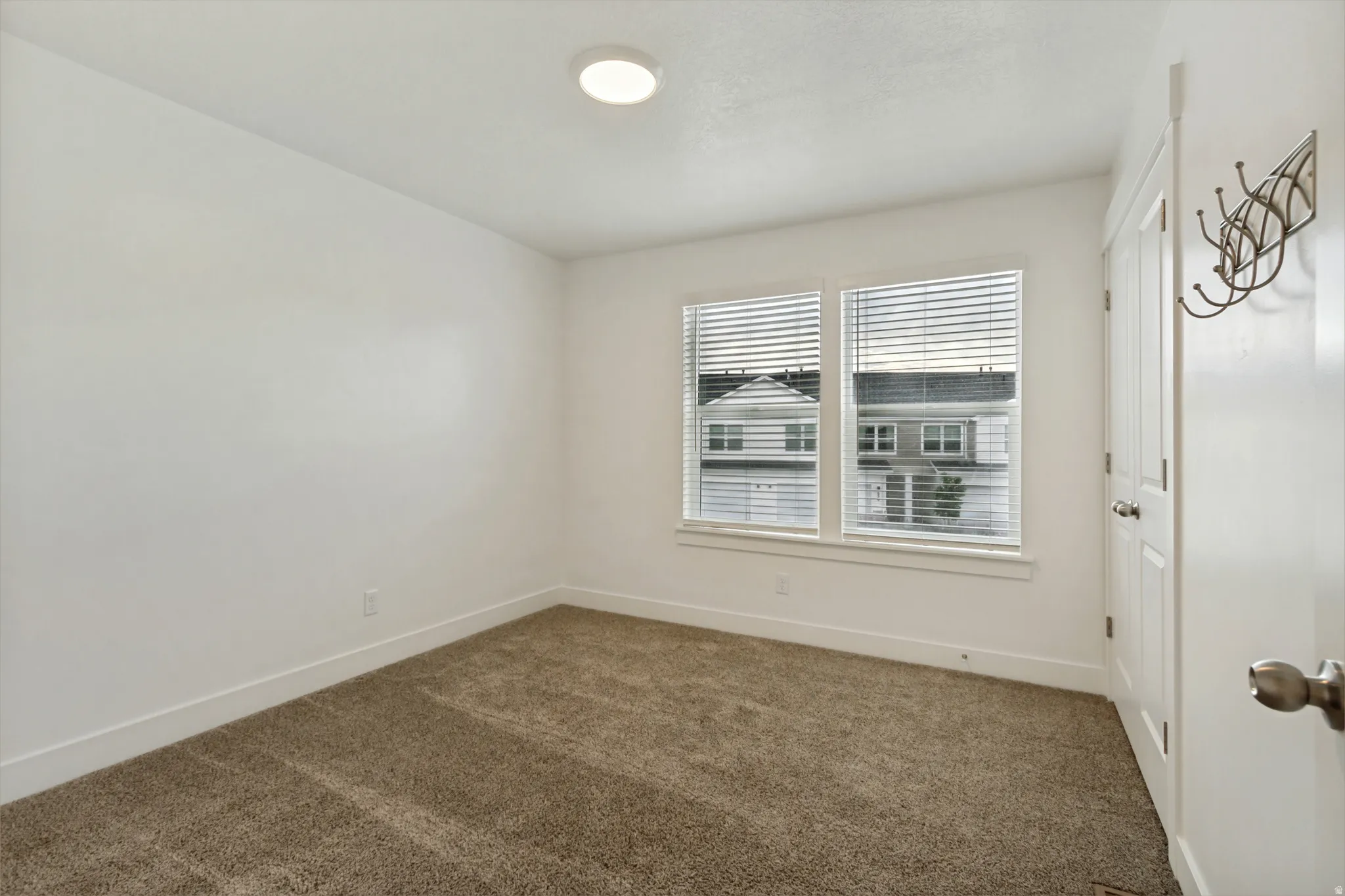 Bedroom three, 2 tone wall finishes, two pane windows, light brown carpet, white baseboards, and a flush mount ceiling light fixture
