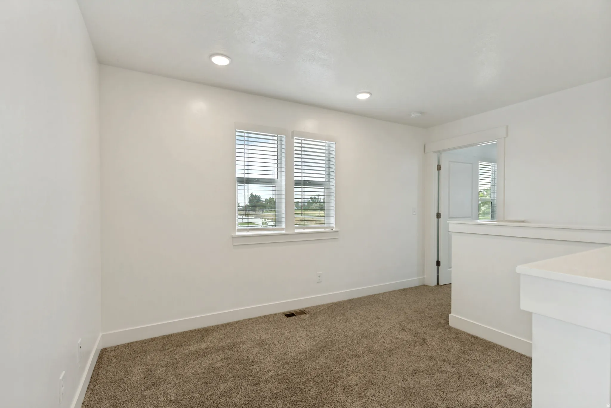 Loft featuring white walls, recessed lighting and two large windows