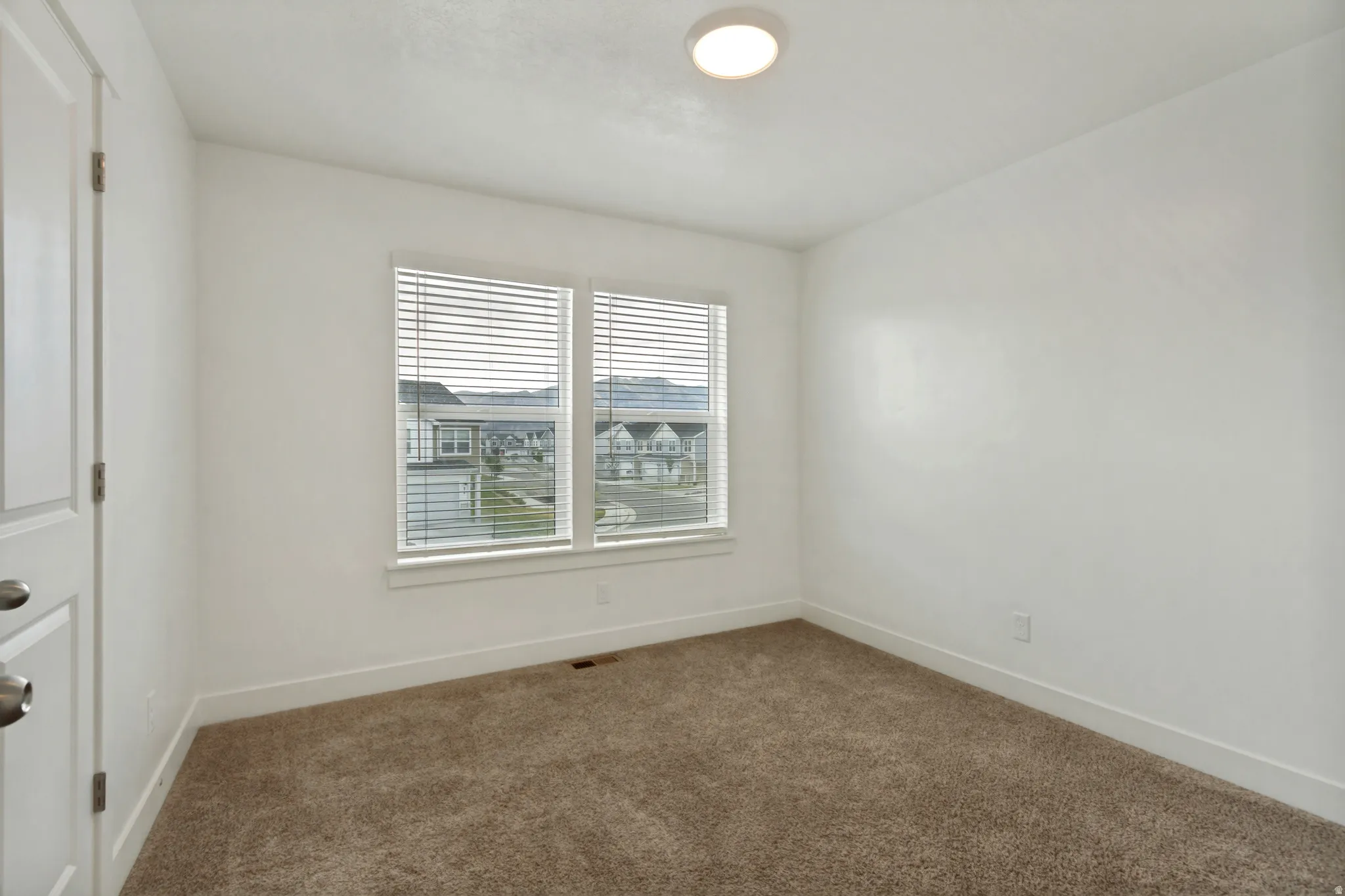 Bedroom two, 2 tone wall finishes, two pane windows, light brown carpet, white baseboards, and a flush mount ceiling light fixture