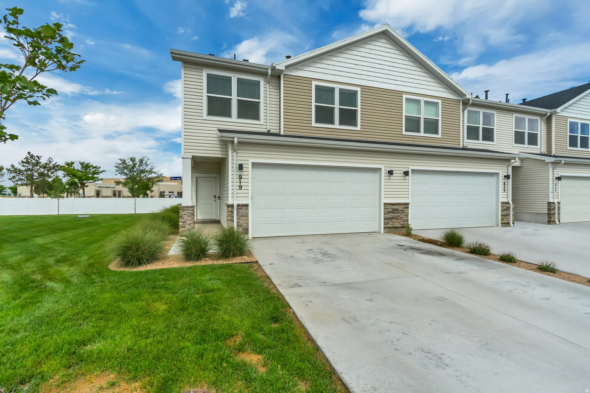 Modern townhome exterior featuring concrete driveway, and stone accents