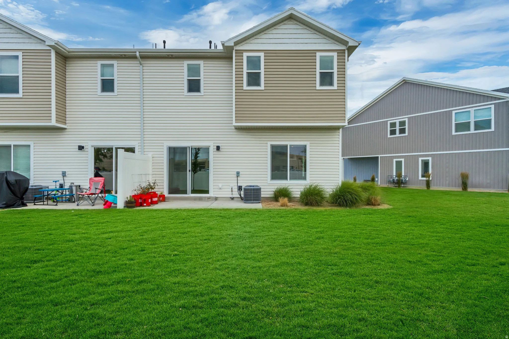 End unit, no backyard neighbors featuring a spacious green lawn with a concrete patio directly accessible via two sliding glass doors