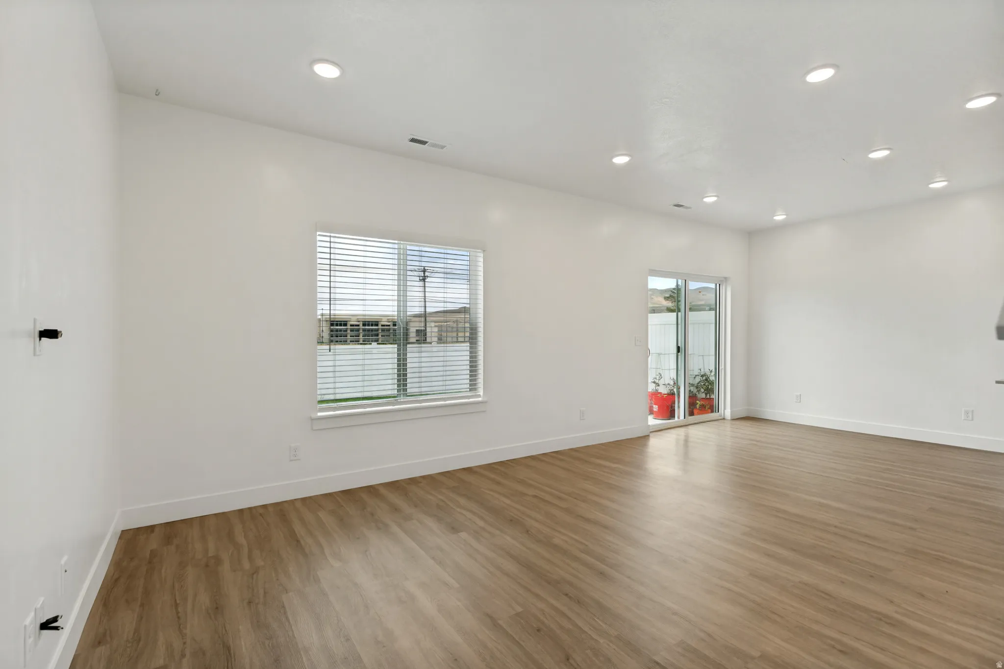 Spacious room featuring wood-finish flooring, recessed lighting, and natural lighting
