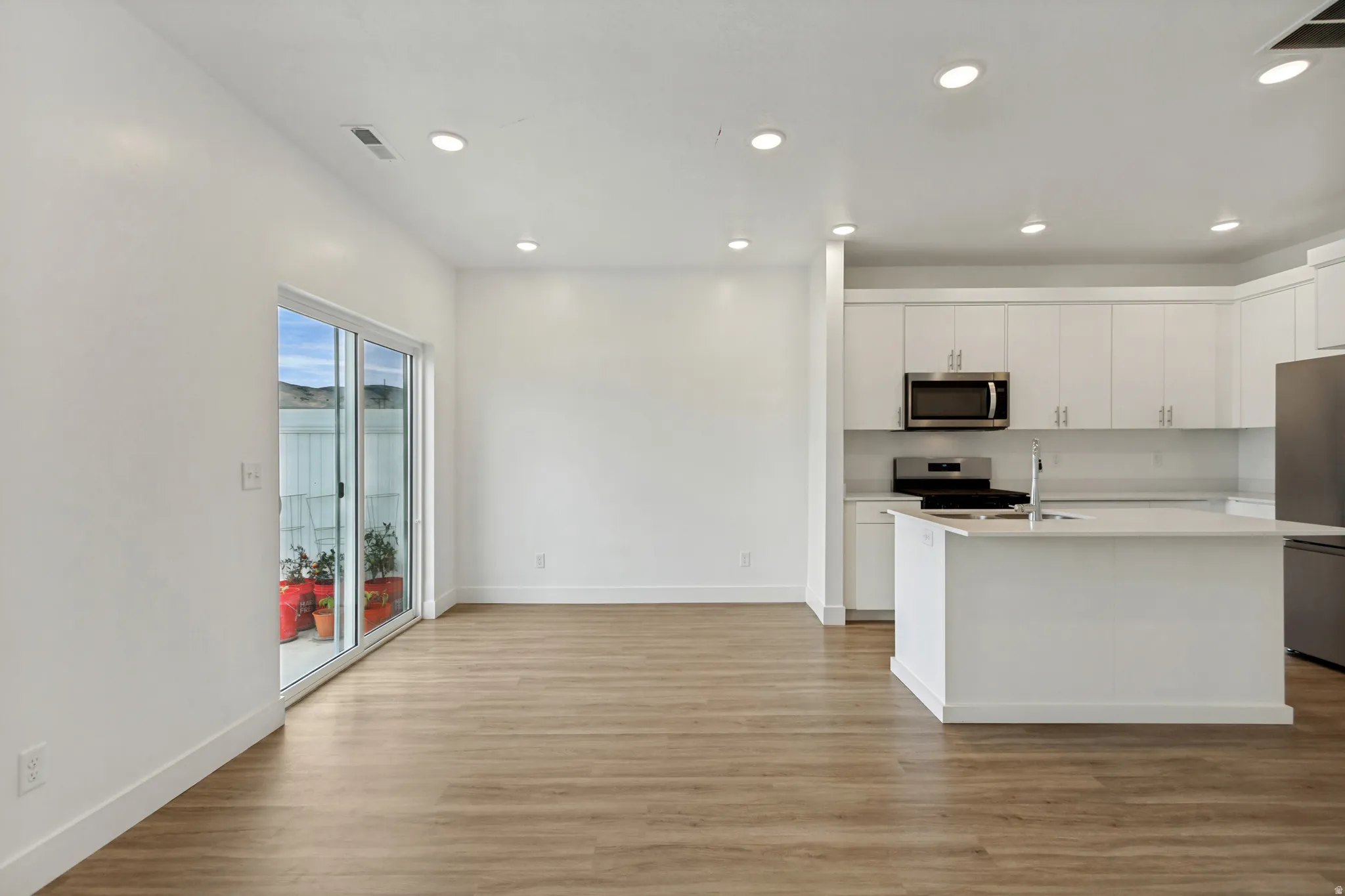 Open-concept living area featuring wood-finish flooring, recessed lighting, and a sliding glass door to an outdoor patio