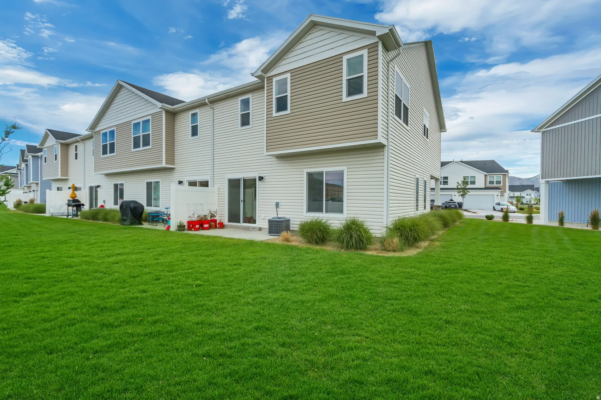 End unit, no backyard neighbors featuring a spacious green lawn with a concrete patio directly accessible via two sliding glass doors