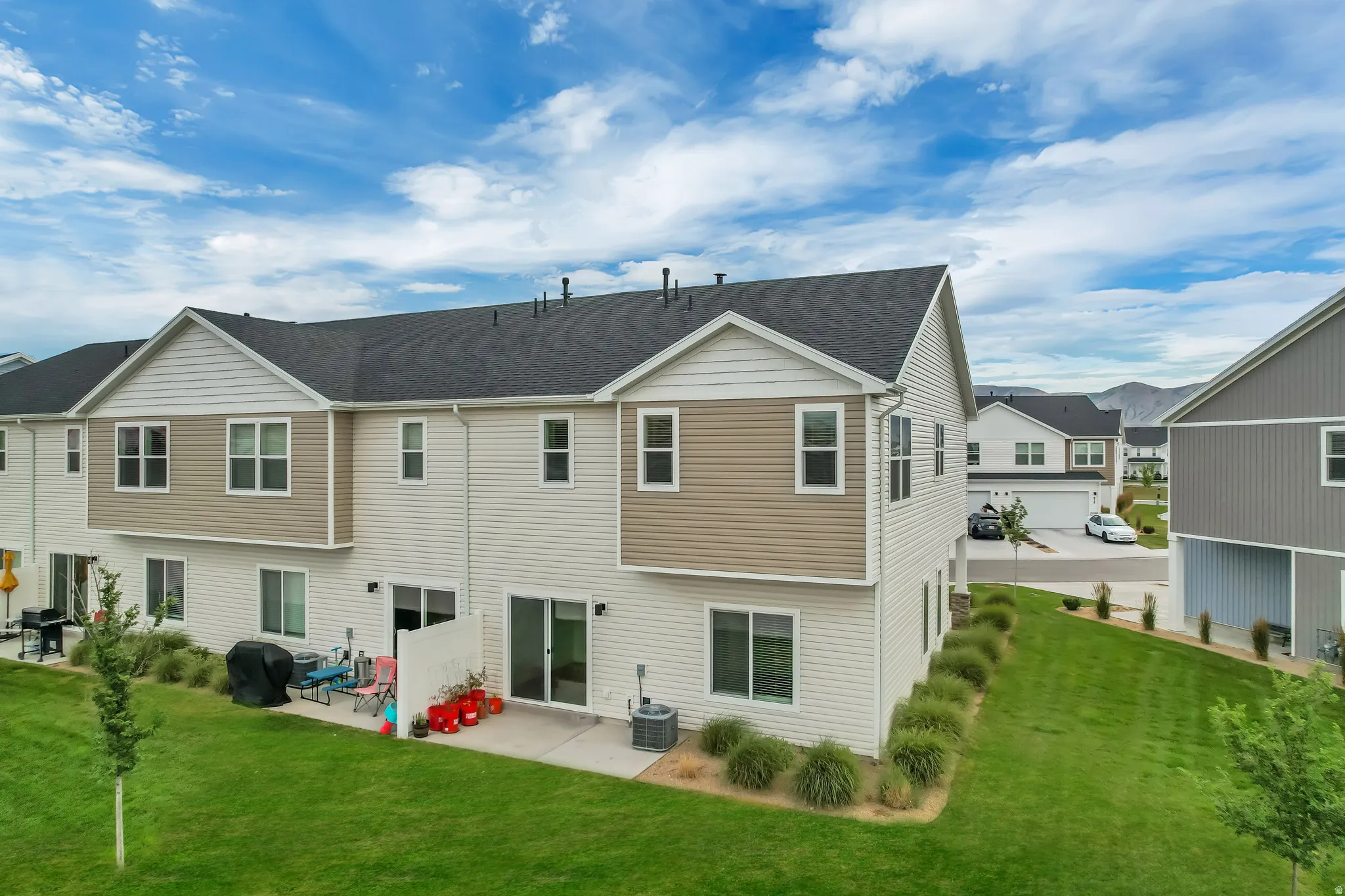 Rear exterior featuring a manicured lawn, concrete patio, and a sliding glass door