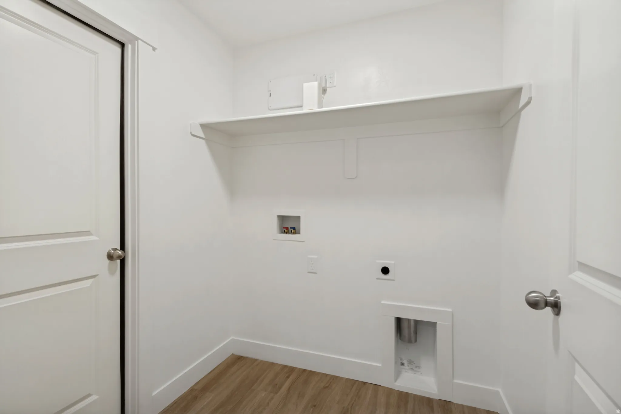Utility area featuring a built-in shelf, wood-finish flooring, and white baseboards