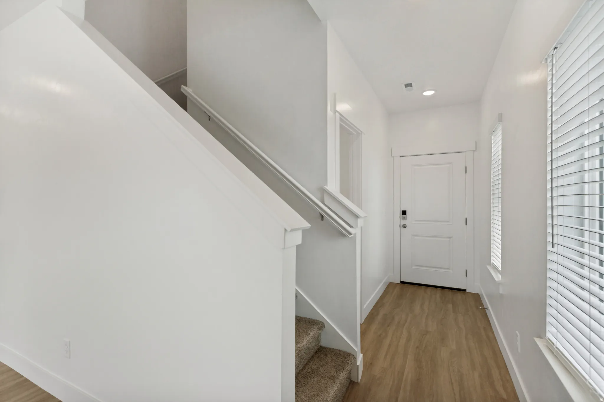 Foyer featuring wood-finish flooring, white paneled entry door, recessed lighting, and a staircase to the upstairs