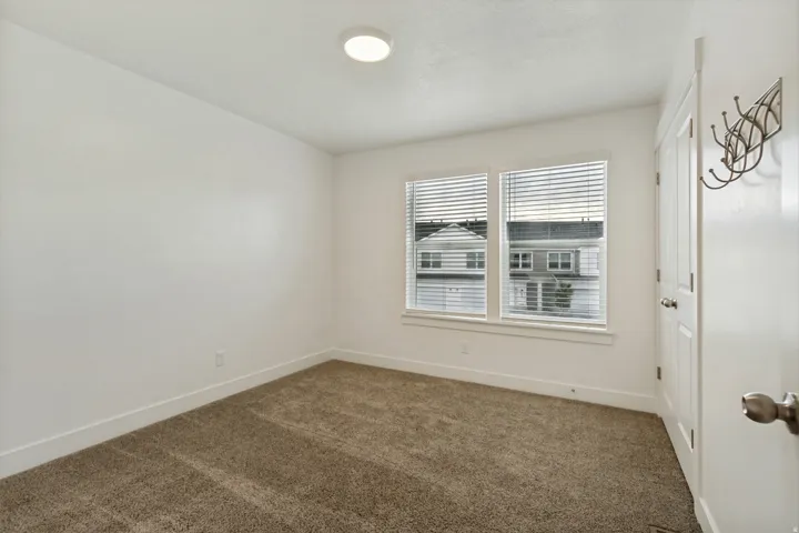 Bedroom three, 2 tone wall finishes, two pane windows, light brown carpet, white baseboards, and a flush mount ceiling light fixture