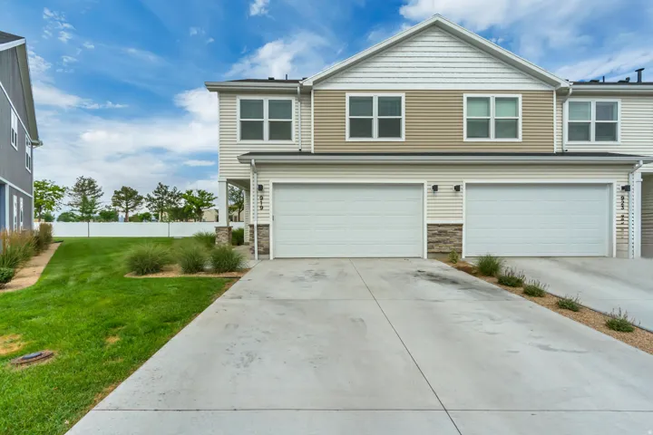 Modern townhome exterior featuring concrete driveway, and stone accents