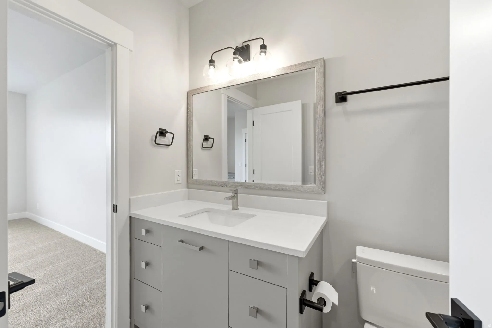 Bathroom featuring a single vanity with light gray cabinetry, white countertop, and contemporary brushed nickel faucet