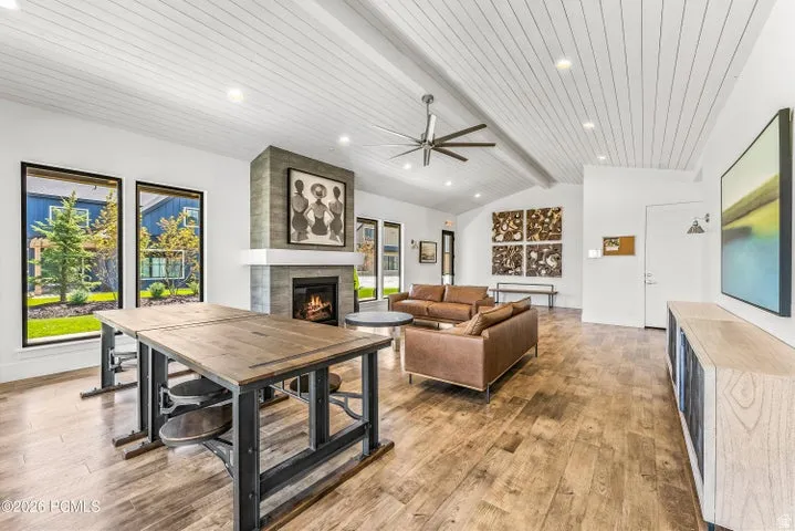 Expansive gathering room featuring wood-finish flooring, a vaulted plank ceiling, and a stone-clad fireplace with a white mantel