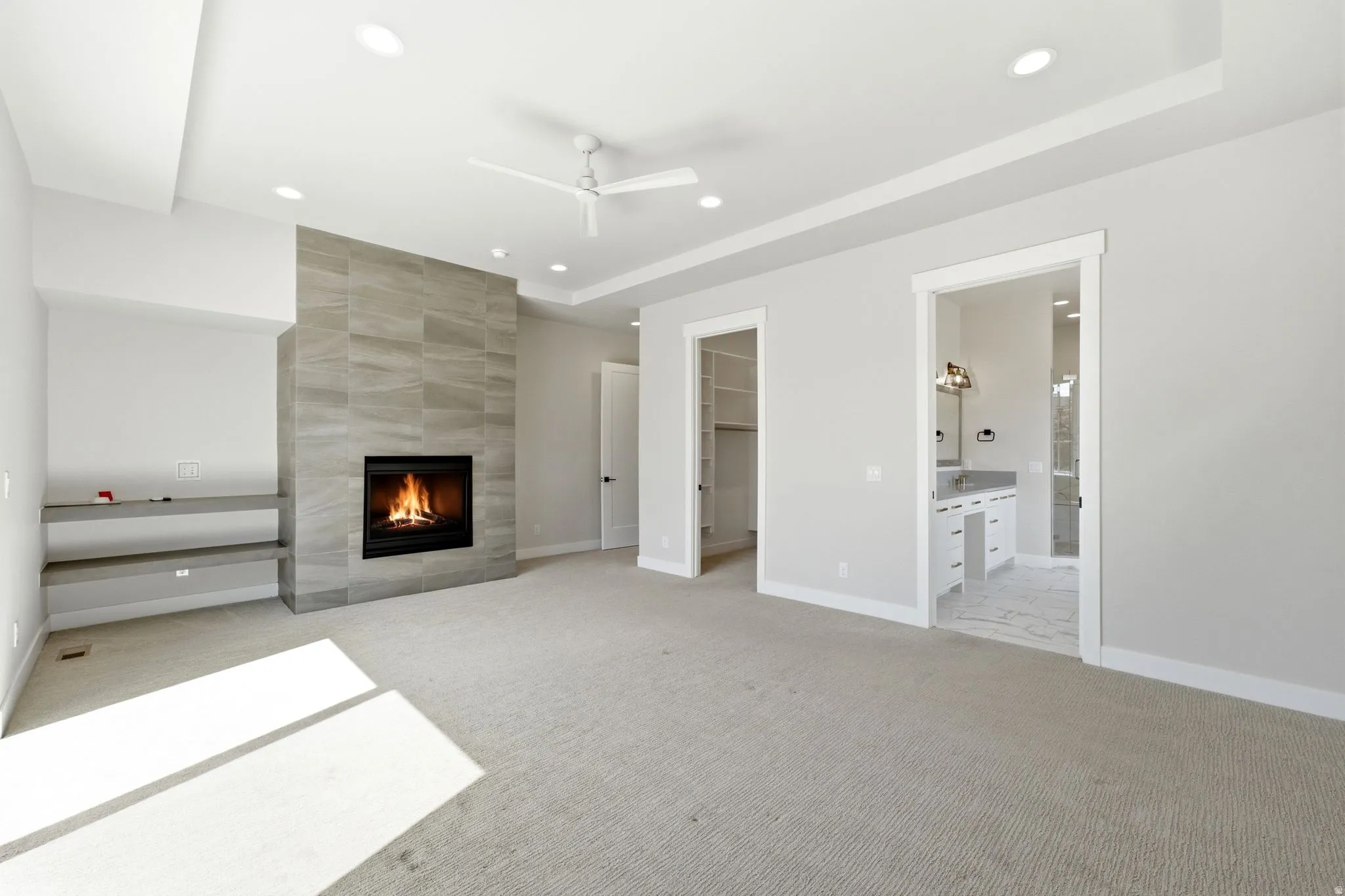 Spacious room featuring a floor-to-ceiling tiled fireplace, built-in shelving, recessed lighting, and a ceiling fan