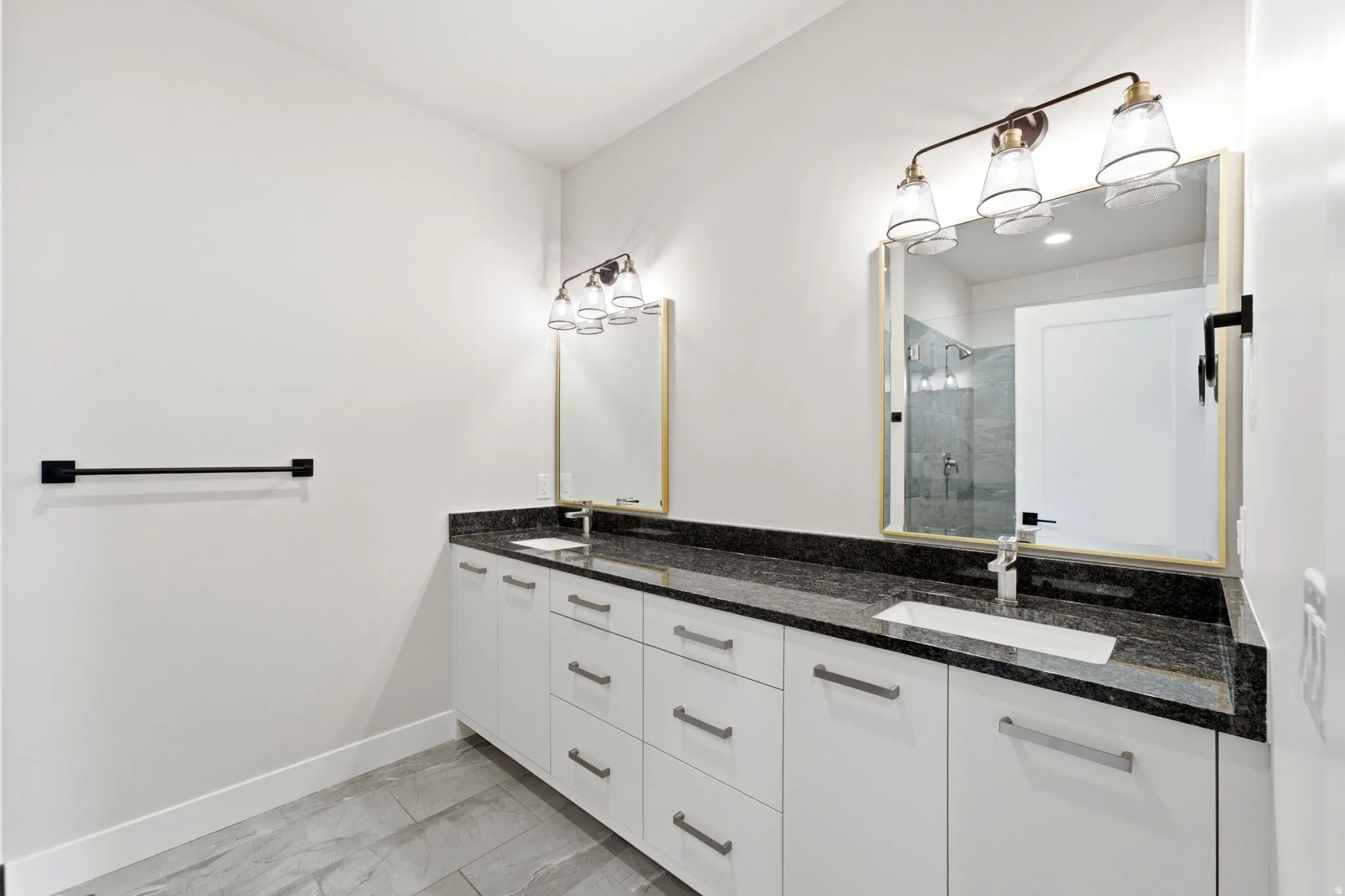 Double vanity with white cabinetry, dark stone countertop, and two integrated rectangular sinks
