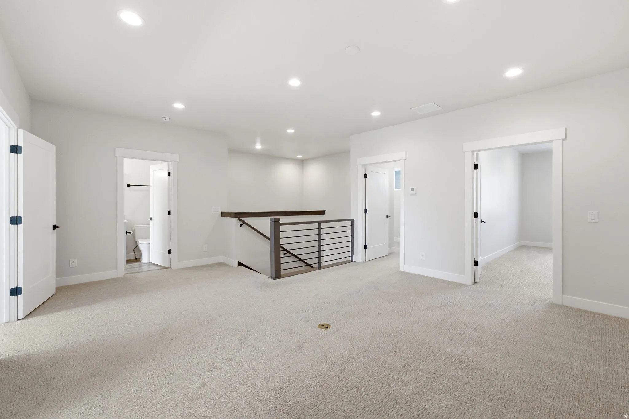 Second-story landing featuring recessed lighting, light neutral carpet flooring, and a contemporary horizontal metal baluster railing
