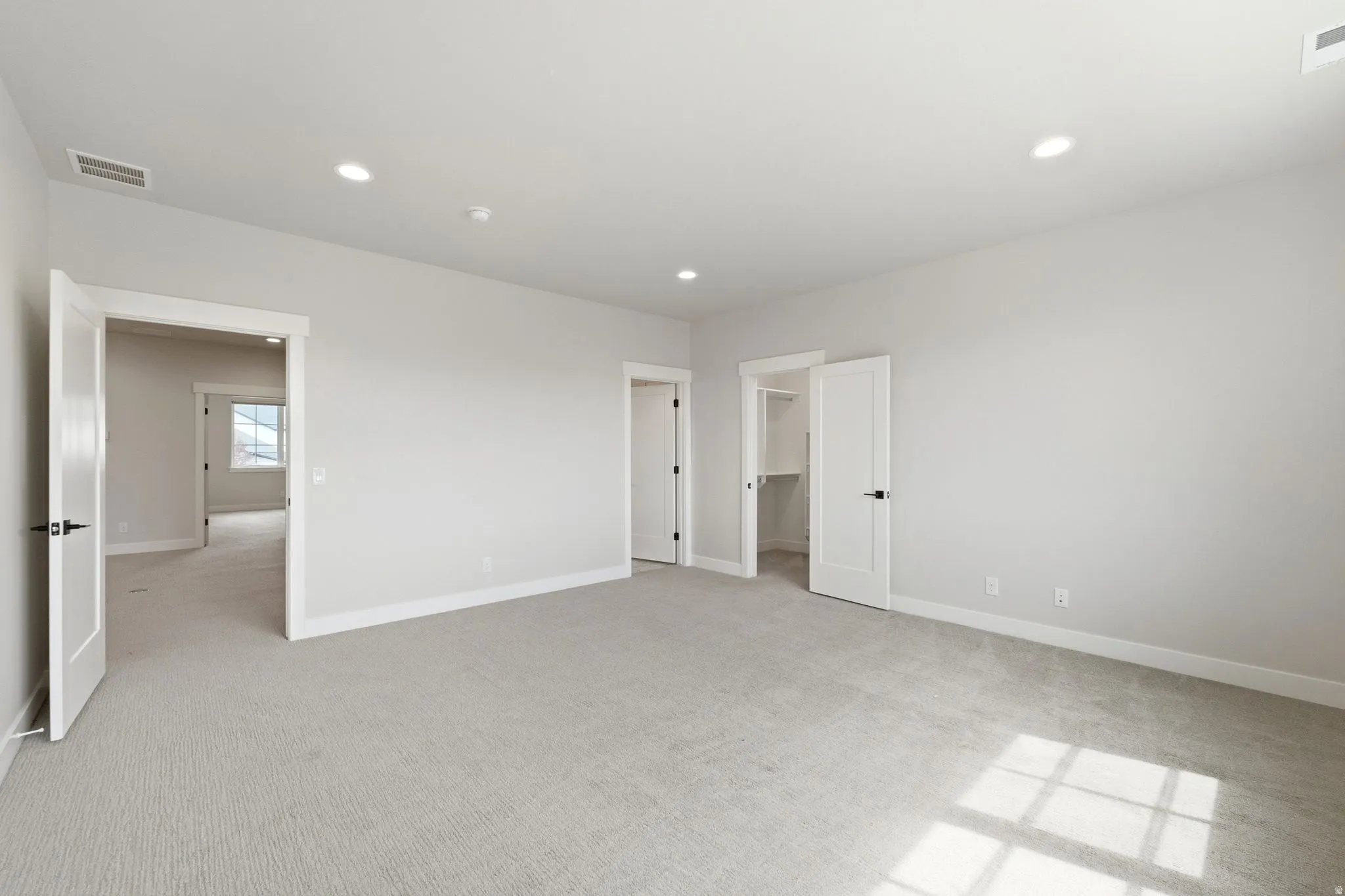 Spacious room with light gray carpeting and white walls