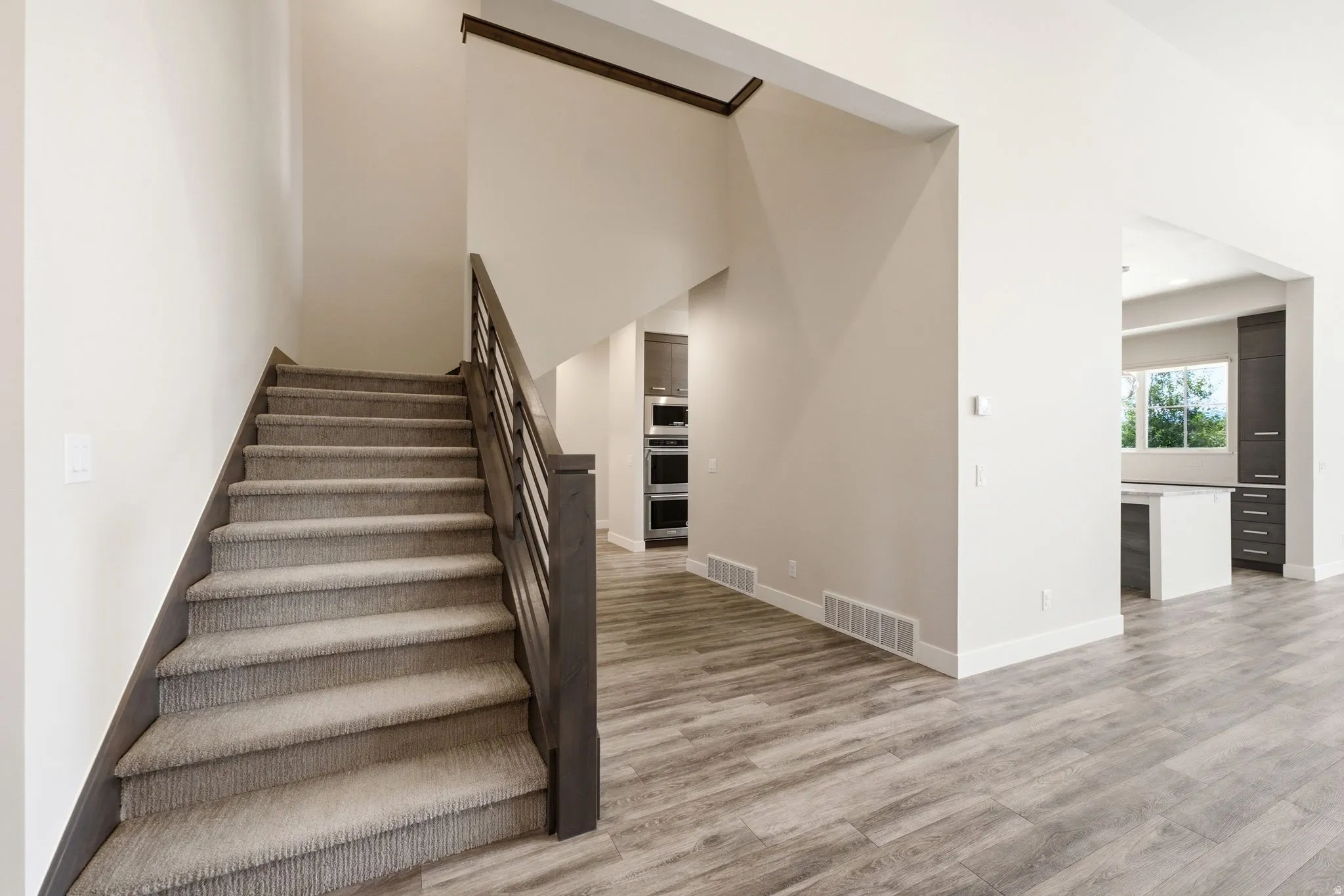 Carpeted staircase with dark wood-finish handrail and black metal balusters