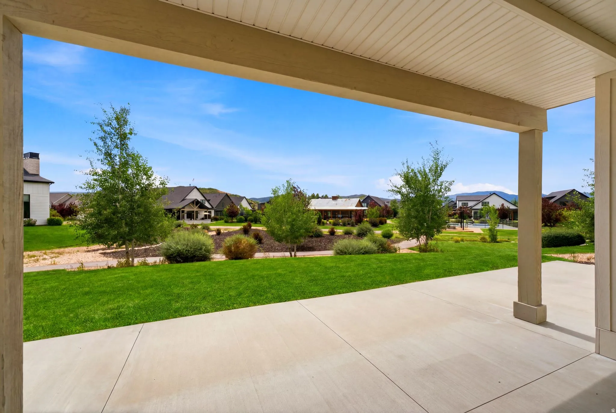 Covered concrete patio overlooking a manicured lawn