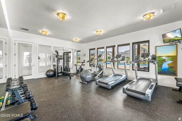 Dedicated fitness space featuring rubber flooring, multiple large windows, and recessed lighting