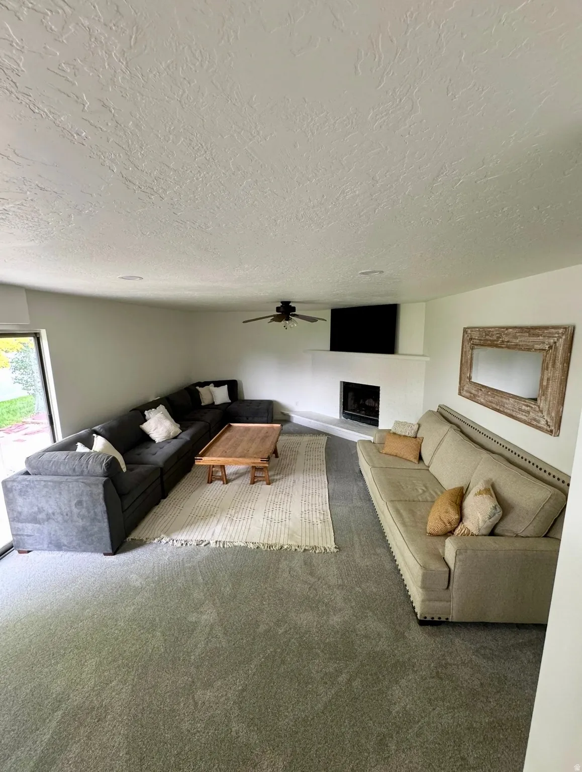 Spacious living area featuring light gray carpeting and a white textured ceiling