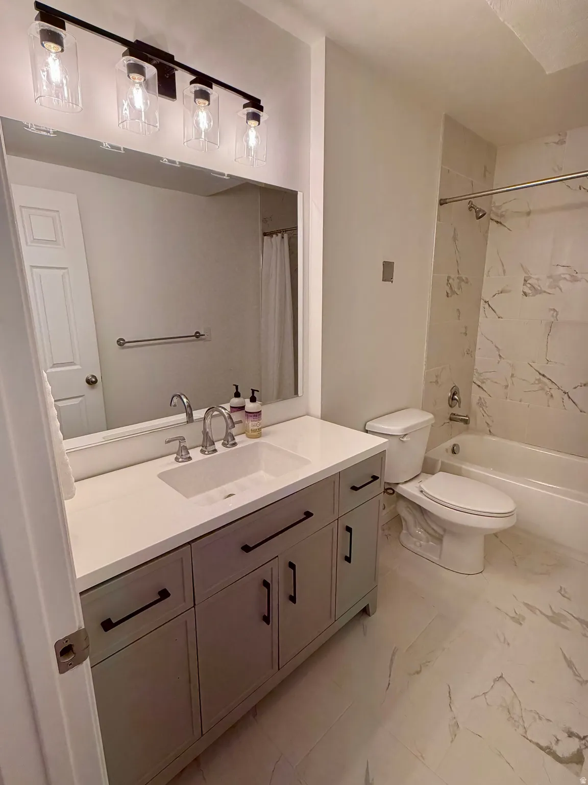 Bathroom featuring a single vanity with stone-finish countertop, undermount sink, and matte black hardware
