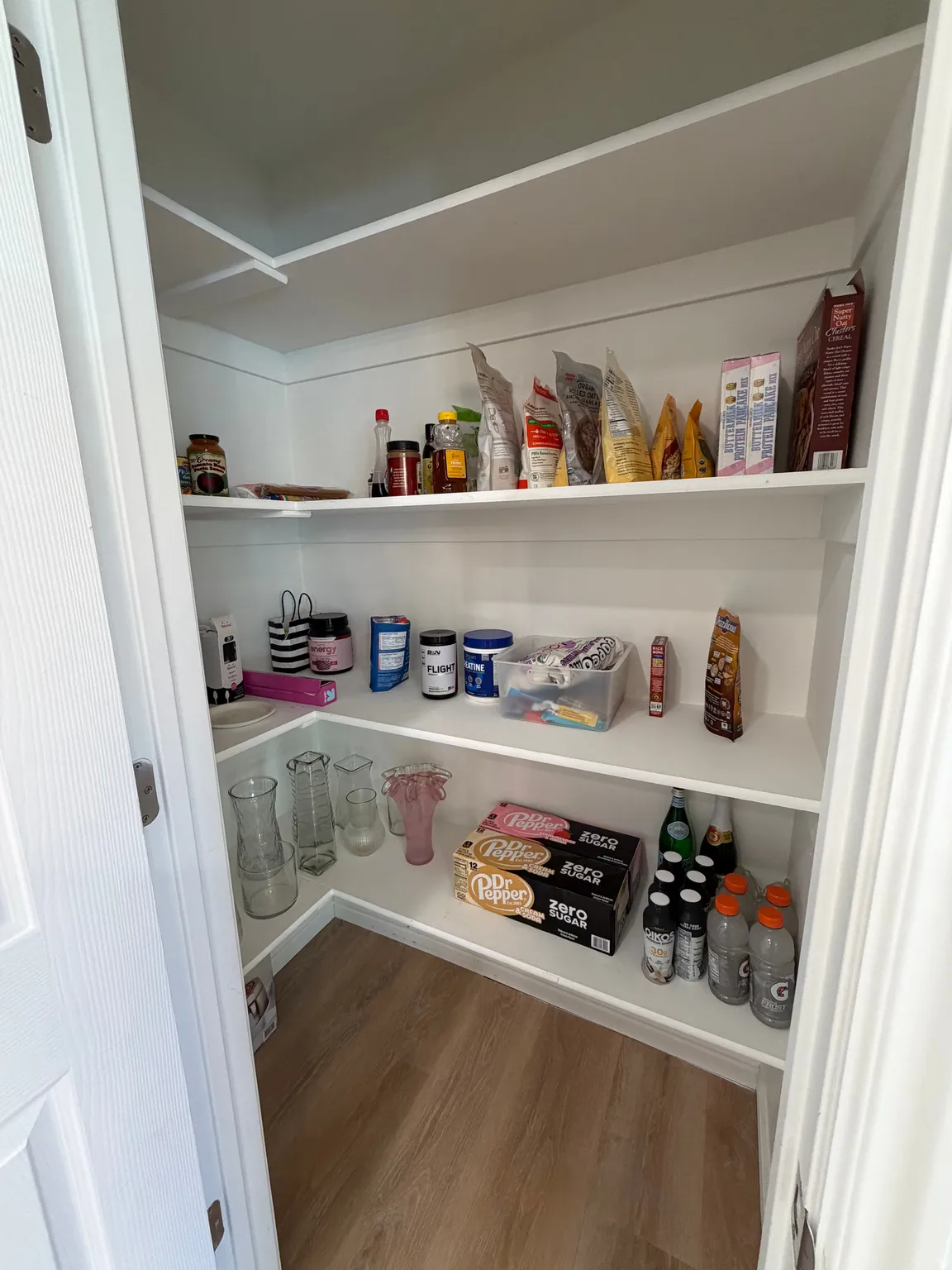 Walk-in pantry featuring white shelving, light wood-finish flooring, and white trim