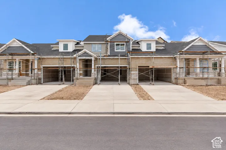 Multi-unit exterior featuring dark shingle roofing, horizontal siding, stone veneer accents, dormer windows, and attached garage bays