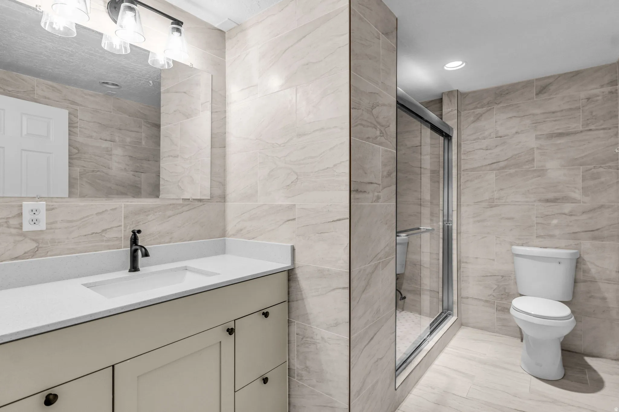Contemporary bathroom featuring extensive light-toned tile work throughout