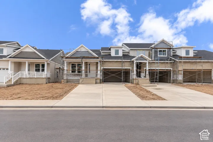 Multi-unit residential exterior featuring mixed-material siding, gabled rooflines, covered front porches with columns, and concrete driveways