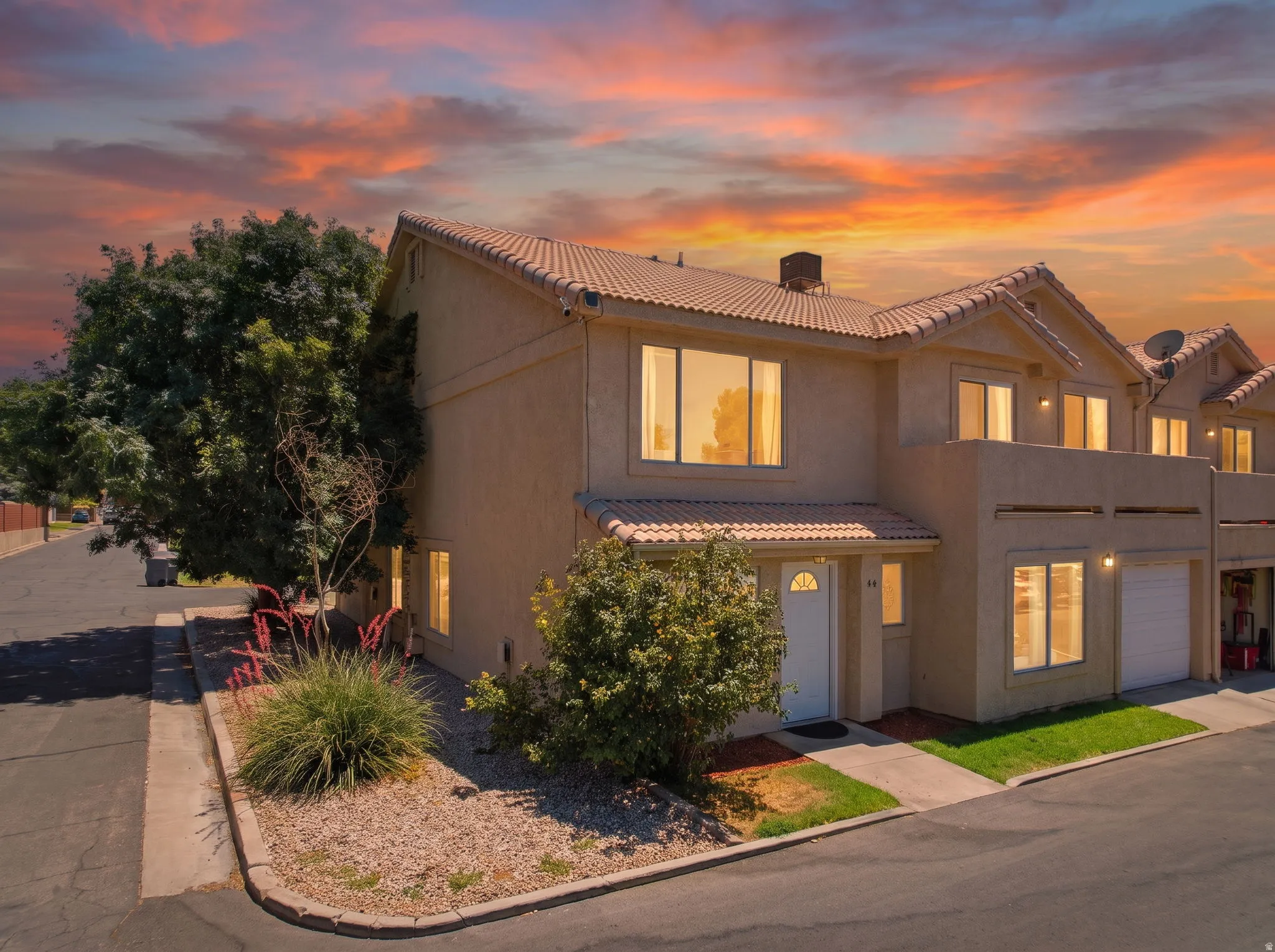 Two-story stucco exterior featuring a tiled roof, integrated garage, and a white entry door