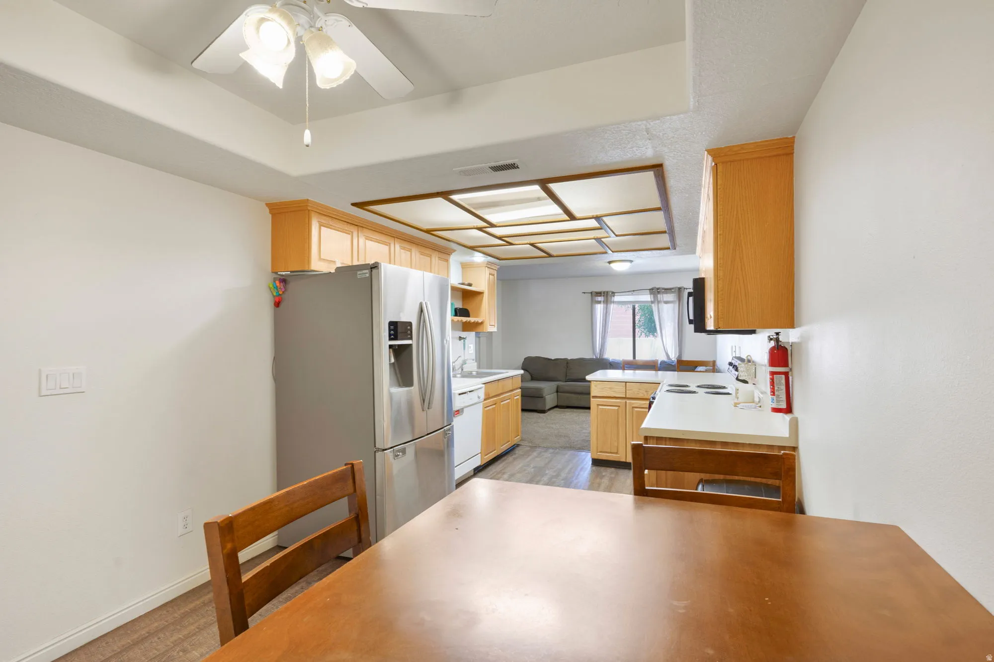 Kitchen area featuring wood-finish cabinetry, stainless steel refrigerator, and white countertops