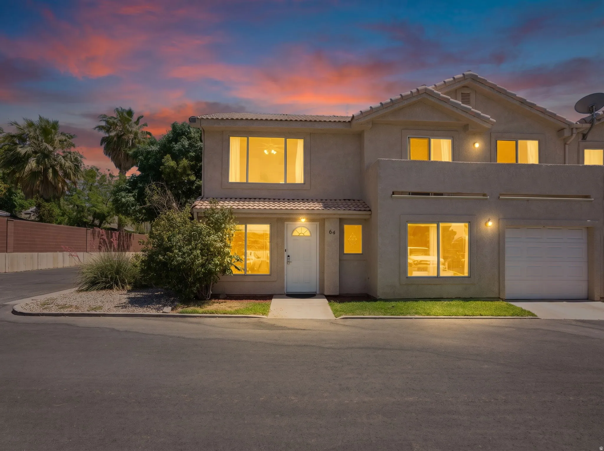 Two-story stucco exterior featuring a two-car garage, white front door, and multiple windows