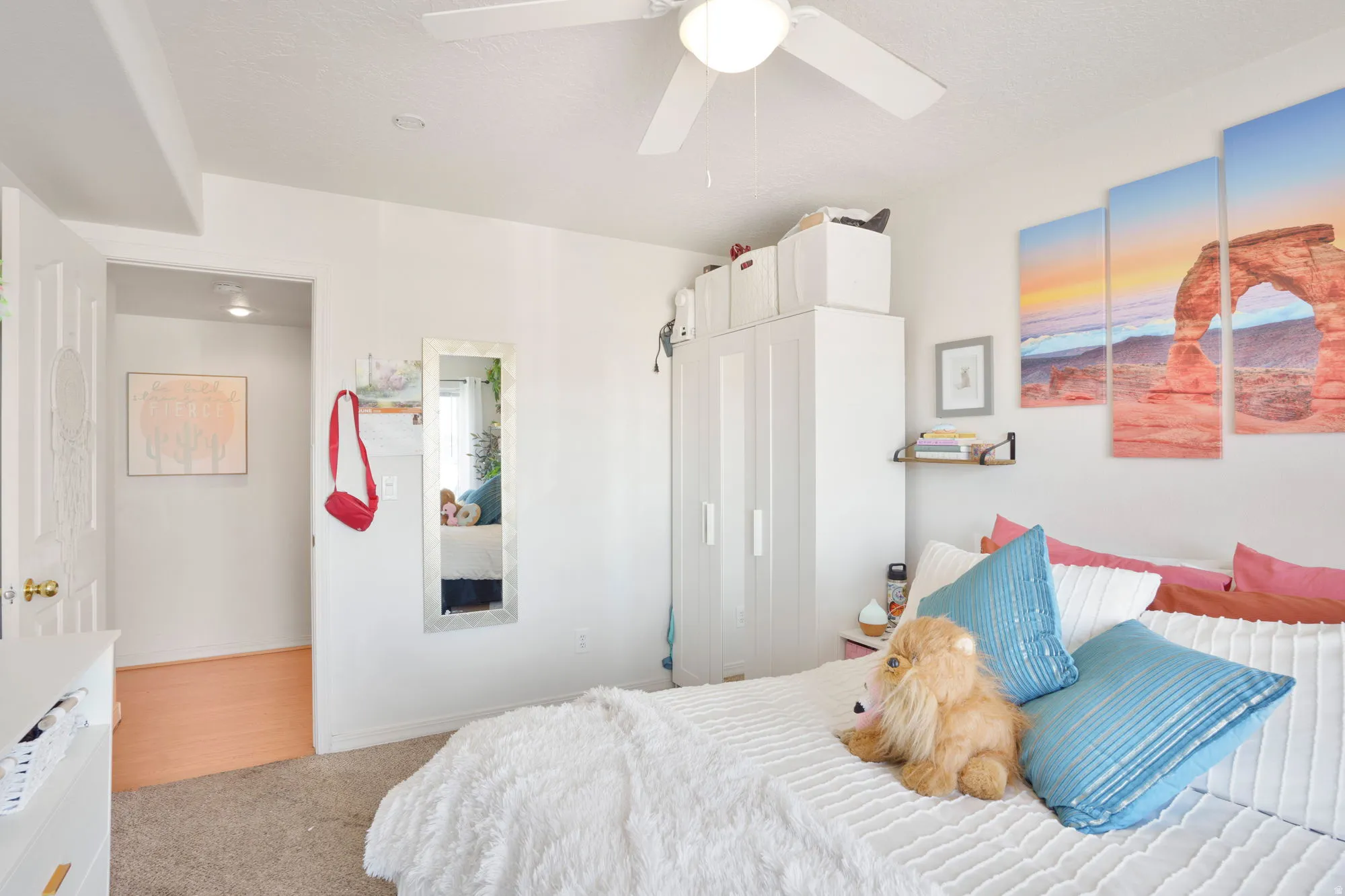 Bright bedroom with a ceiling fan, plush carpet flooring, and white walls