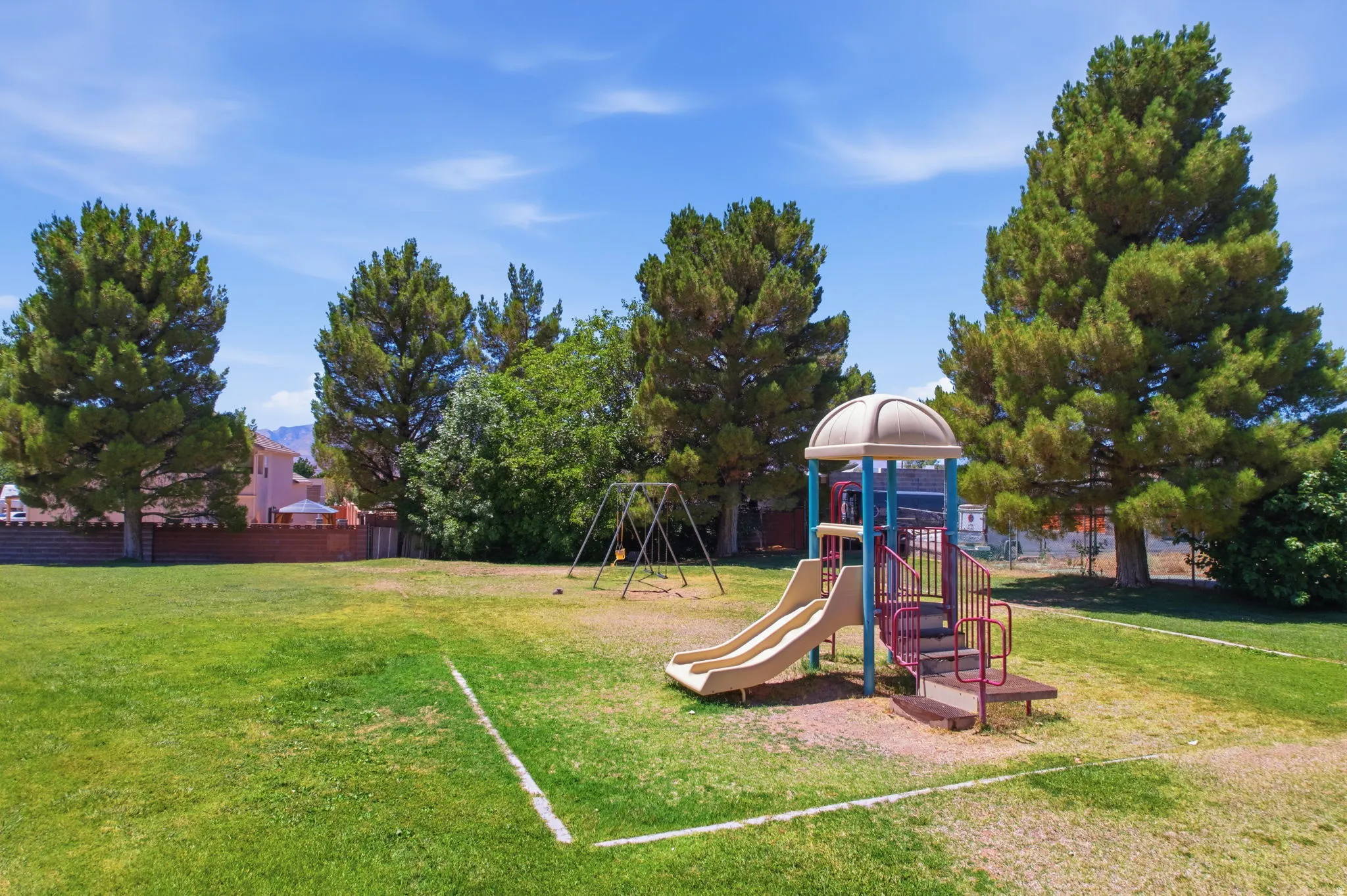 Community park area featuring a playground structure with a slide and a separate swing set