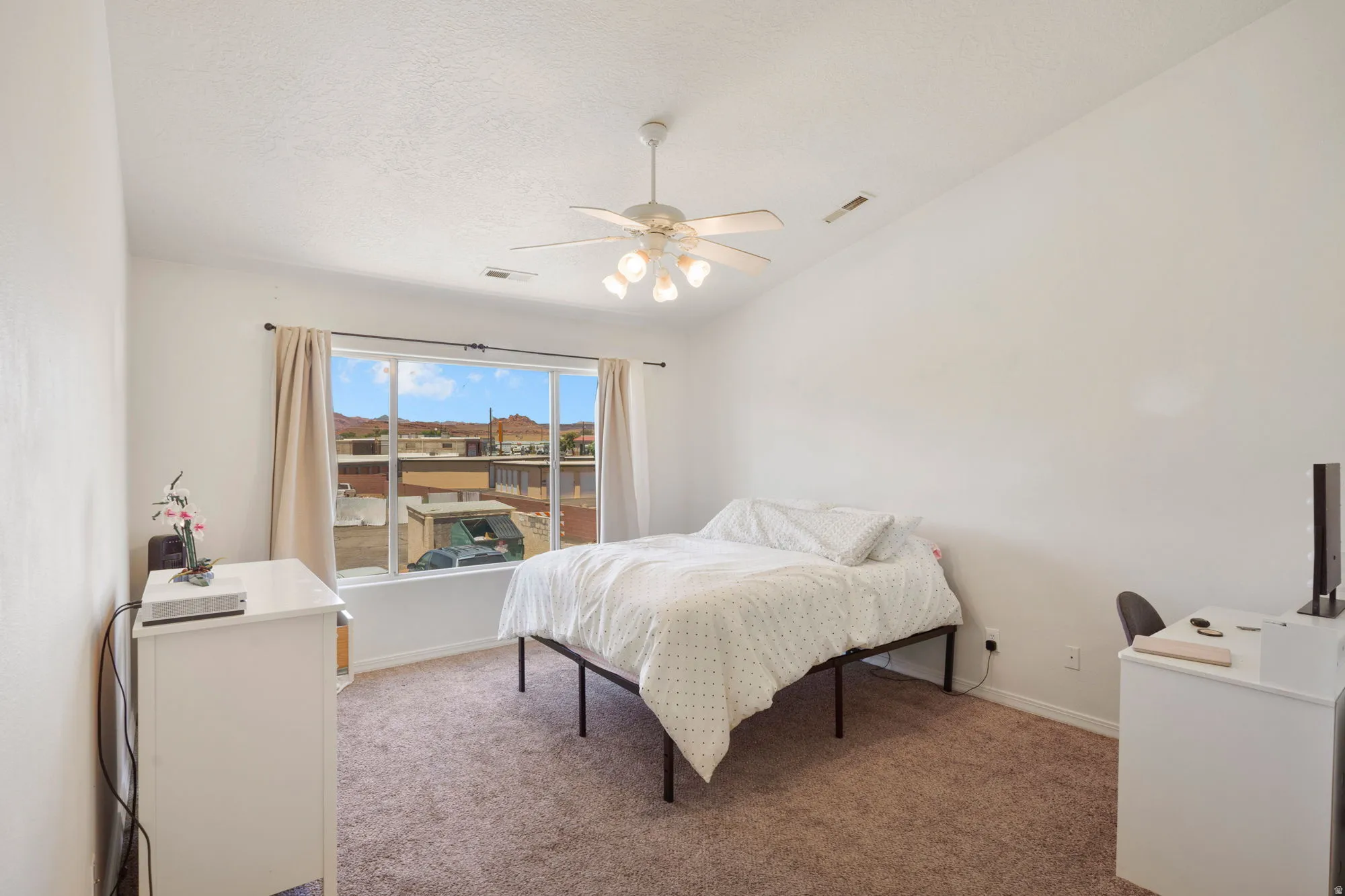 Vaulted ceiling bedroom with a ceiling fan light fixture and neutral-toned carpet flooring
