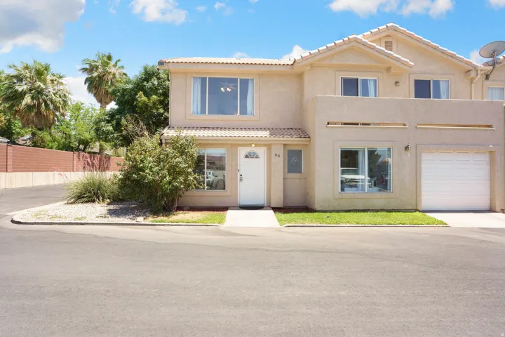 Two-story stucco residence featuring a white paneled garage door and a complementary white front entry door