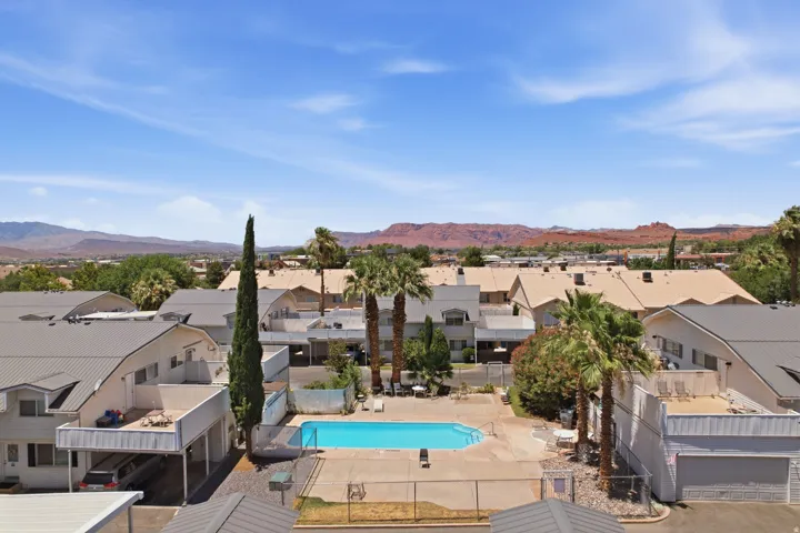 Central swimming pool with surrounding concrete decking, fenced perimeter, and nearby palm trees