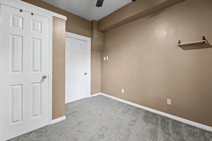 Room featuring textured tan walls and gray carpet flooring