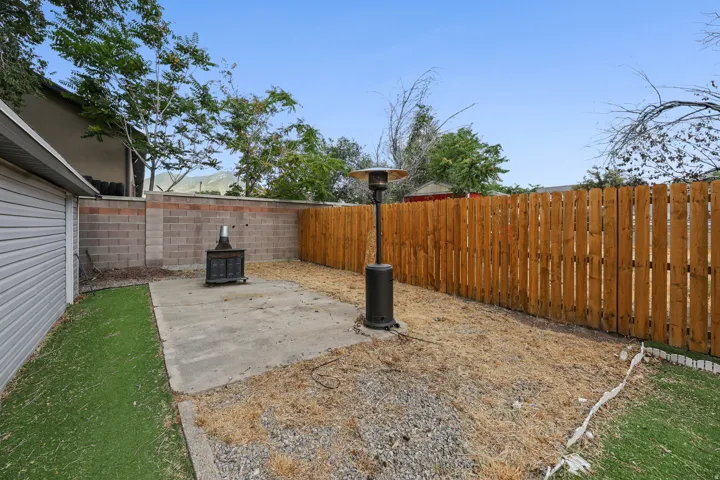 Rear yard featuring concrete patio, artificial turf, and a wood privacy fence