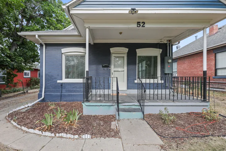 Entry facade featuring a covered porch with white columns, wrought iron railings, and a number plaque