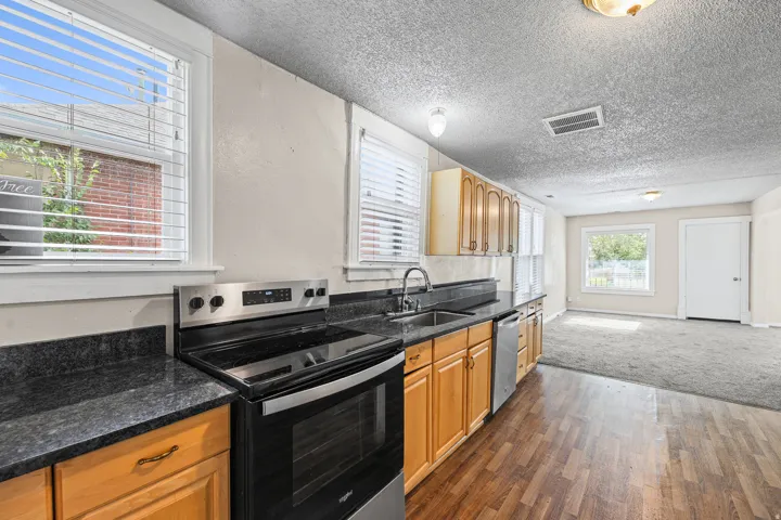 Kitchen featuring wood-finish flooring, dark stone-look countertops, and light wood cabinetry