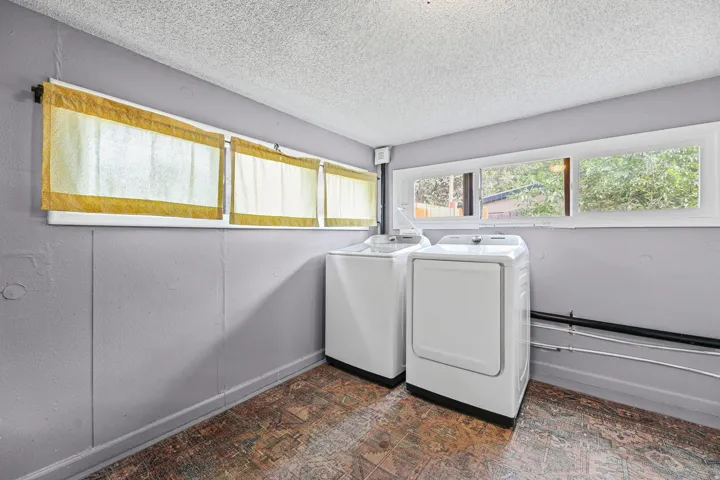 Dedicated laundry area featuring a patterned floor, light gray walls, and multiple windows