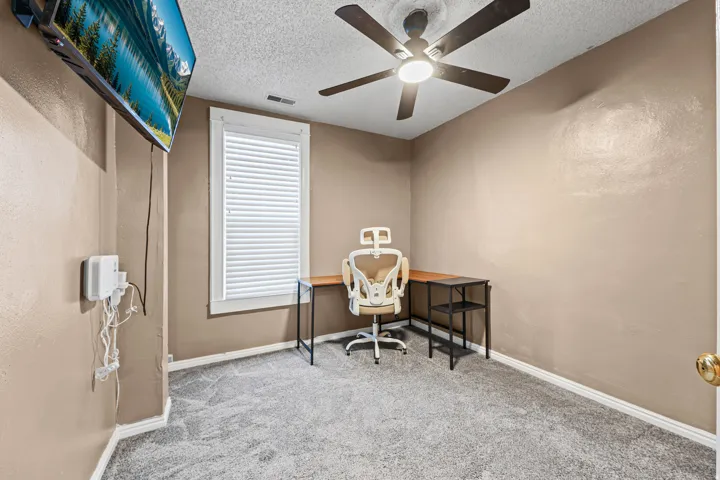 Carpeted room featuring a ceiling fan with integrated lighting, a window with horizontal blinds, and neutral-toned walls