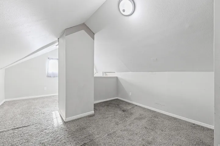 Attic room with sloped ceilings and wall-to-wall carpeting