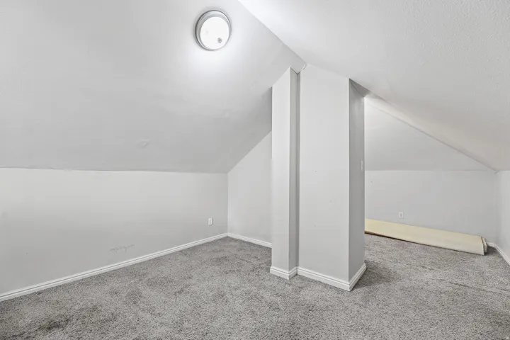 Carpeted room with sloped ceilings and light wall paint